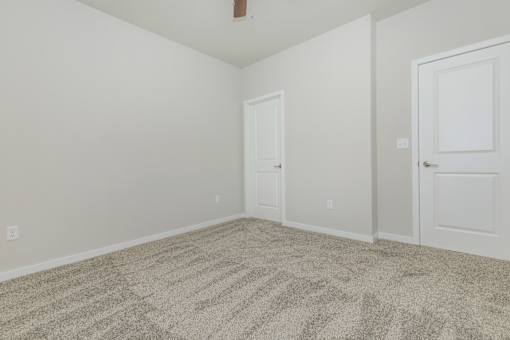 A room with two doors and carpeted floor.