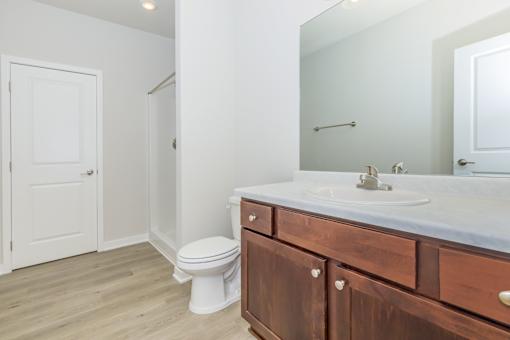 A bathroom with a toilet, sink, and mirror.