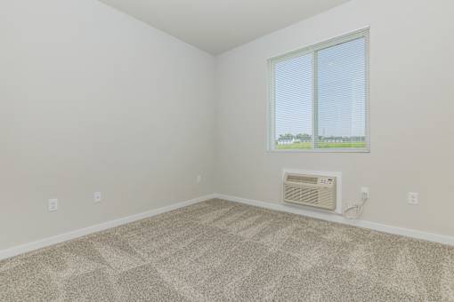 A room with a carpeted floor and a window.