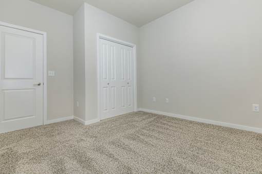 A room with a carpeted floor and two doors.