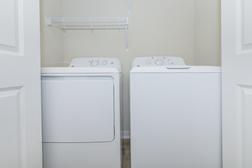 Two white washing machines in a small laundry room.