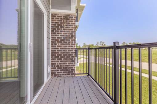 A wooden deck with a black railing and a glass door.