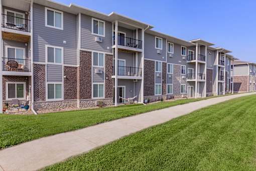 Apartment building with balconies and a lawn in front.