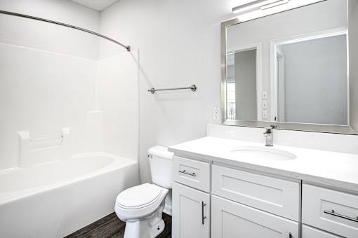 A white bathroom with a toilet, sink, and bathtub.