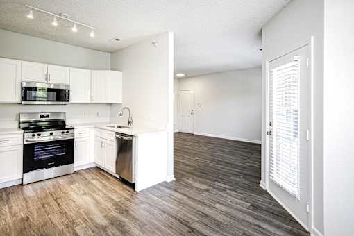 A kitchen with white cabinets and a wooden floor.