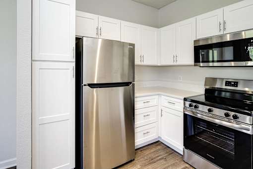 A kitchen with a stainless steel refrigerator, microwave, and oven.