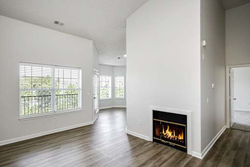 A room with a fireplace and a window with a view of trees.