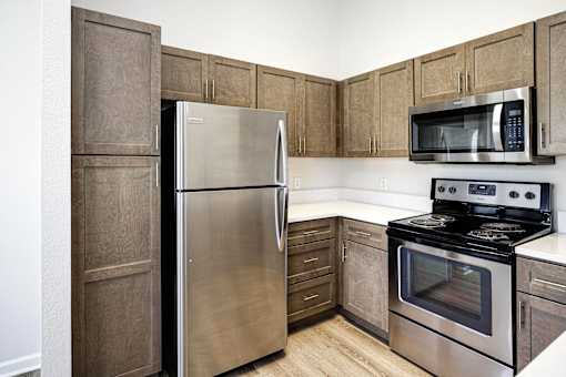 A kitchen with a stainless steel refrigerator, microwave, and oven.