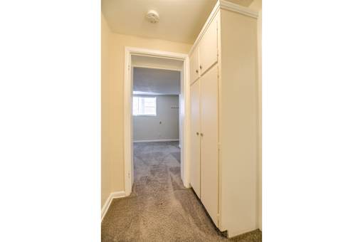 A hallway with a white door and a white cabinet.