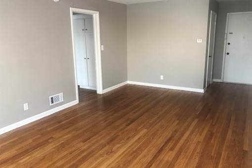 A room with wooden flooring and white walls.