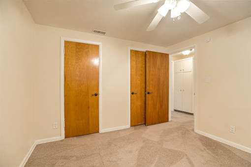 A room with a carpeted floor and two wooden doors.