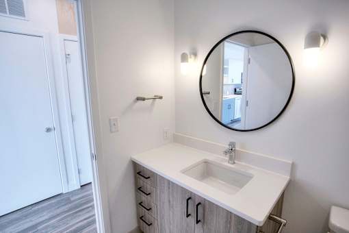 A bathroom with a white sink and a round mirror.