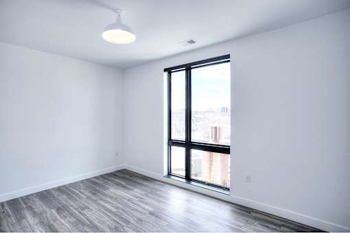 A room with a large window and a grey floor.
