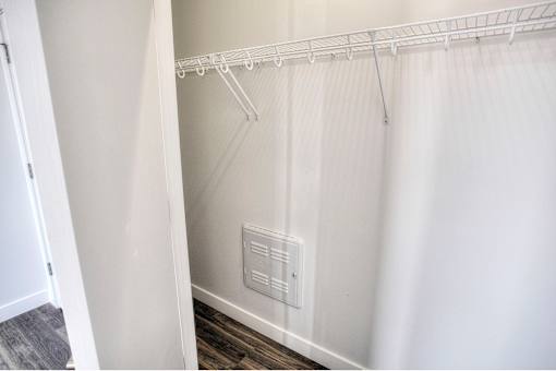 A white closet with a white curtain and a white shelf.