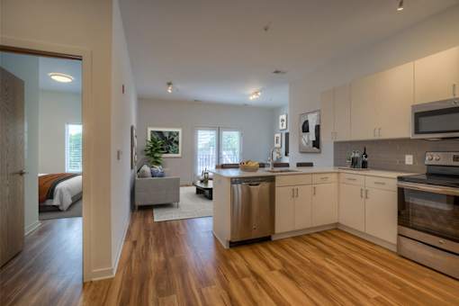 A modern kitchen with wooden floors and stainless steel appliances.