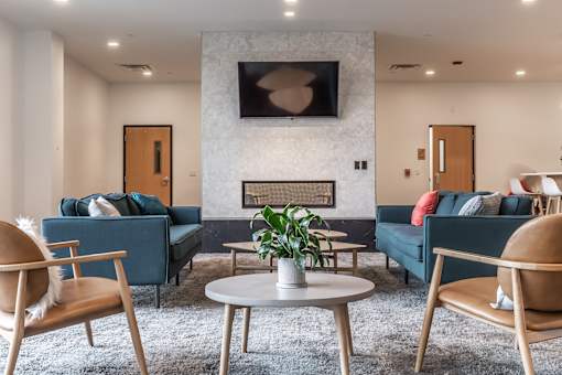 A living room with a blue couch, a white coffee table, and a TV mounted on the wall.