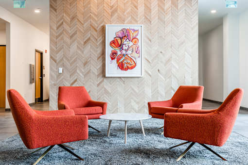 A painting hangs on a wall above a table with chairs around it.
