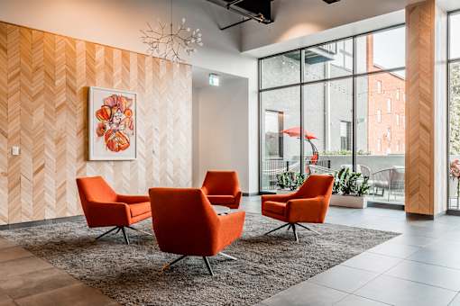 A room with orange chairs and a large painting on the wall.