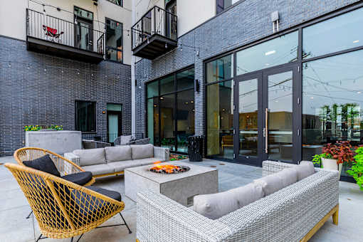 A patio with a black and yellow chair and a grey and white sofa.