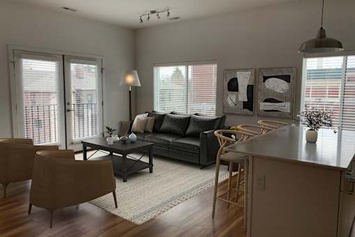 A modern living room with a black couch, a wooden table, and a large window.