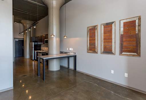 A room with a table and three paintings on the wall.