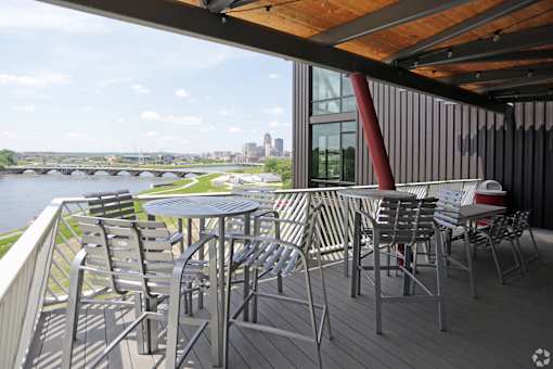 A table and chairs are set up on a balcony overlooking a river.