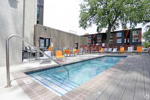 A pool with a metal railing and orange chairs.