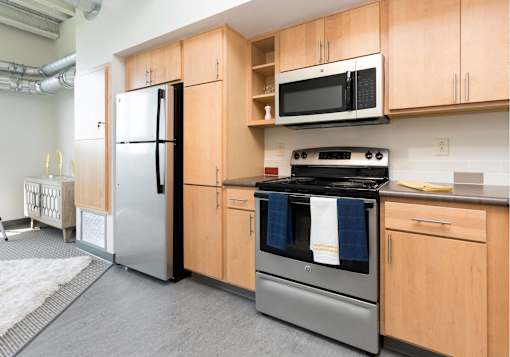 A kitchen with wooden cabinets and a stainless steel refrigerator.