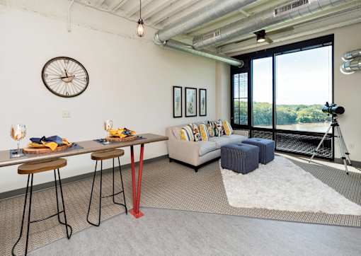 A room with a table, chairs, and a couch with a view of the outdoors.