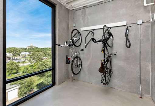 A room with a concrete wall and a bike rack with bikes hanging on it.