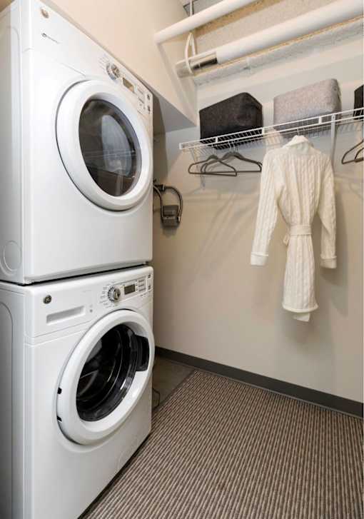 A white washing machine and dryer stacked on top of each other in a laundry room.