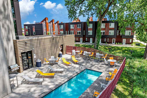 A pool surrounded by chairs and tables in a sunny backyard.