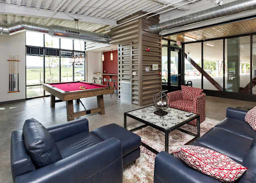 A room with a pool table and leather couches.