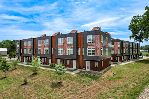 A row of red and brown townhouses with green trees in front.