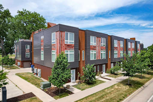 A row of modern townhouses with trees in front.