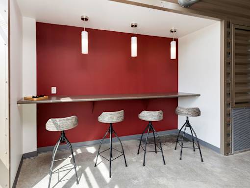 A red wall with a table and three stools in front of it.