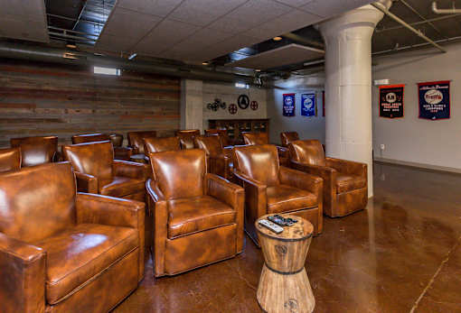 A room with brown leather chairs and a wooden stool.