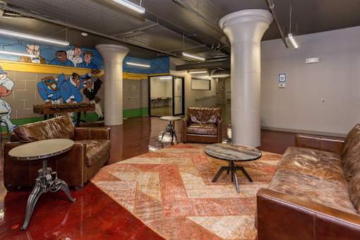 A room with brown leather furniture and a mural on the wall.