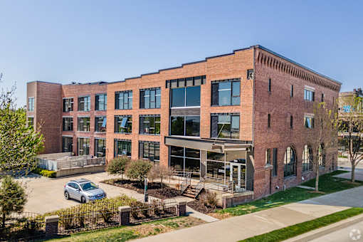 A large red brick building with a parking lot in front.