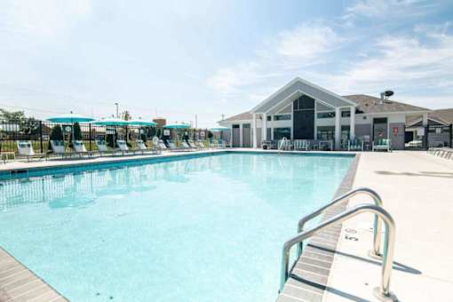 A large swimming pool with a diving board and a building in the background.