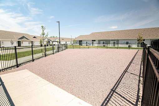 A playground with a black fence and a pink surface.