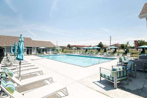 A pool area with sun loungers and umbrellas.