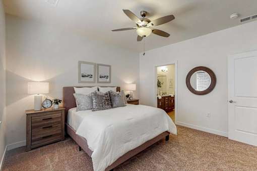 A bedroom with a bed, nightstand, and a ceiling fan.