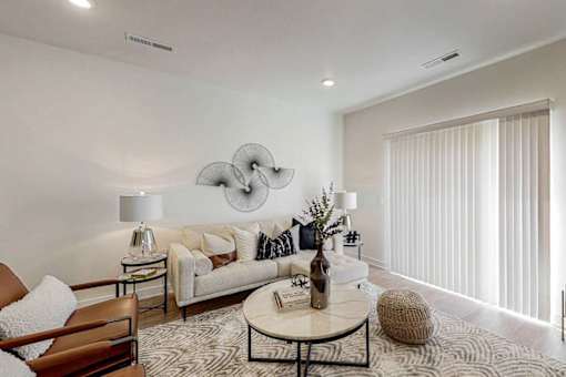 A modern living room with a white sofa, a round coffee table, and a large abstract wall art.