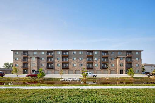 A modern apartment building with a parking lot in front.