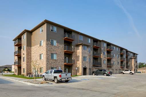 A large apartment building with a parking lot in front.