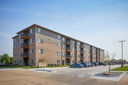 A large apartment complex with a parking lot in front.