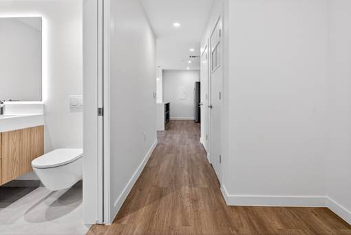 A white bathroom with a toilet and a wooden floor.