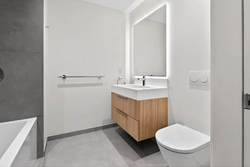 A modern bathroom with a white sink and a wooden cabinet.