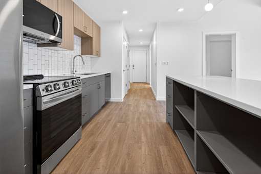 A modern kitchen with dark wood floors and stainless steel appliances.